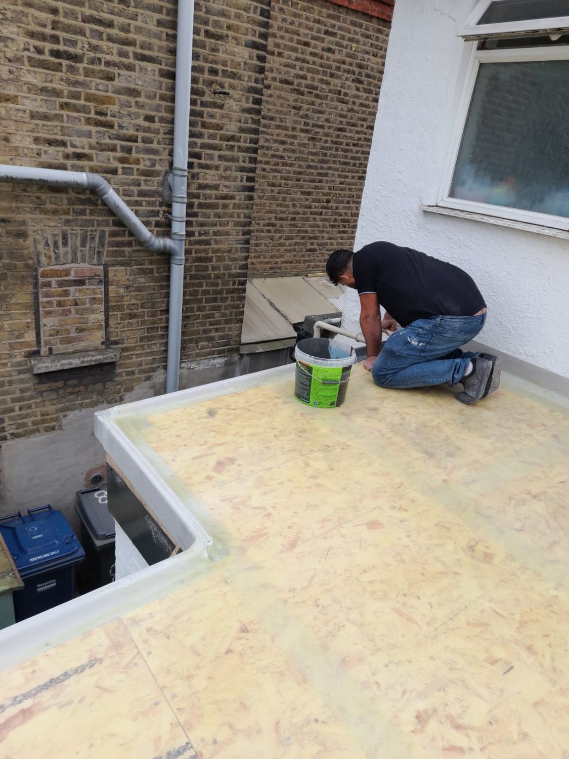 Roofer bonding the new membrane to the deck with adhesive