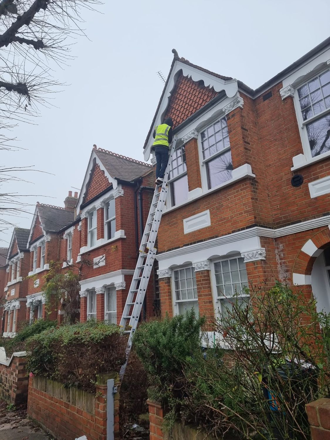 Roofer climbing a ladder to the roof of a London terraced house