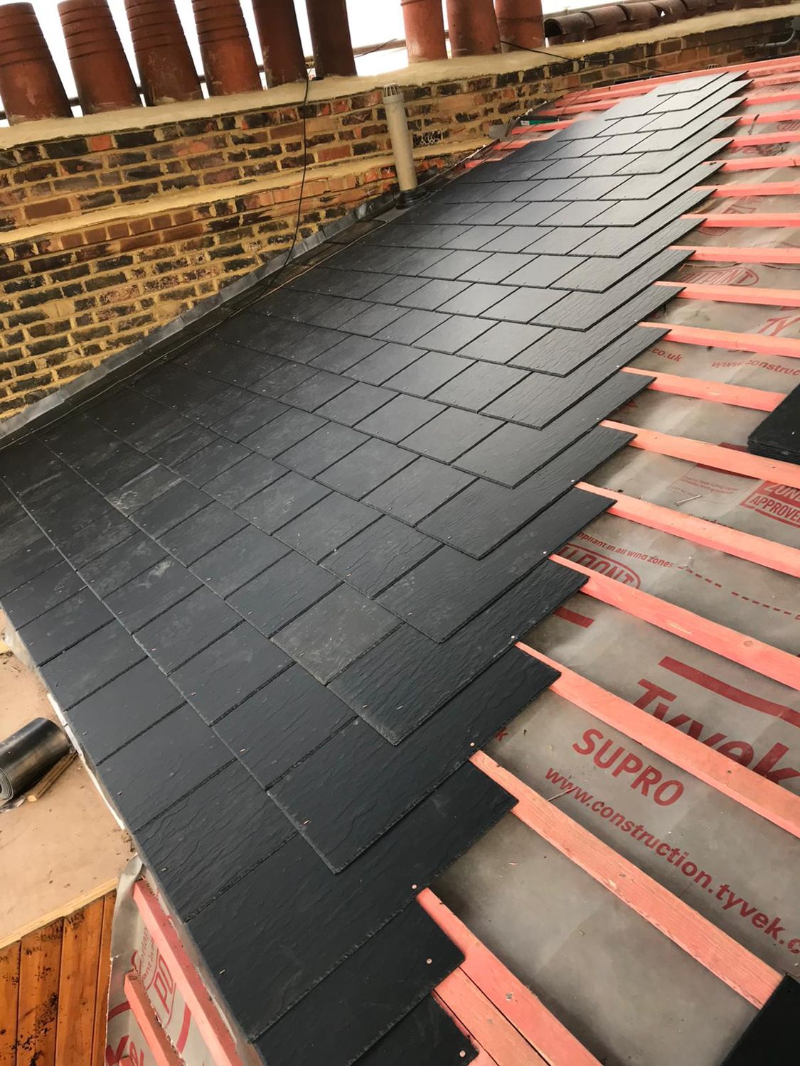 New slate roof being laid over red felt
